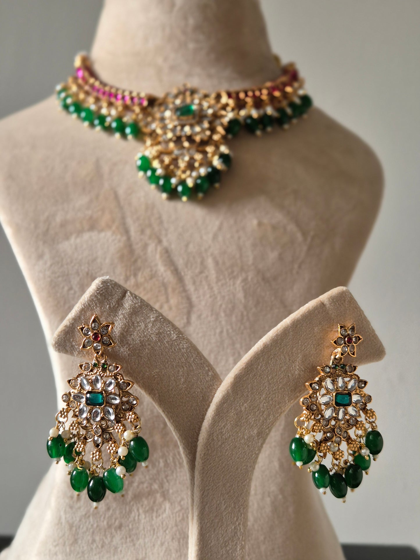 Premium temple necklace set with rich gold, green, and red details photographed on neutral background