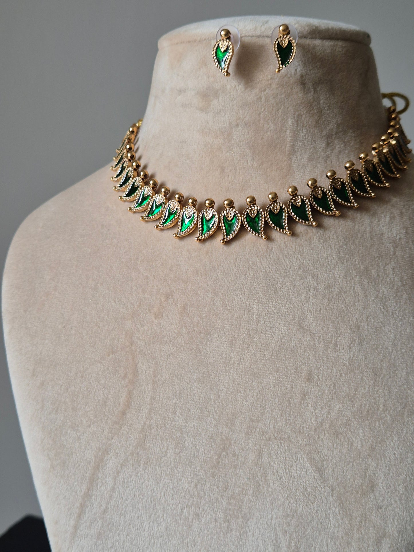 Handcrafted golden necklace set with green stones on neutral background, classic style