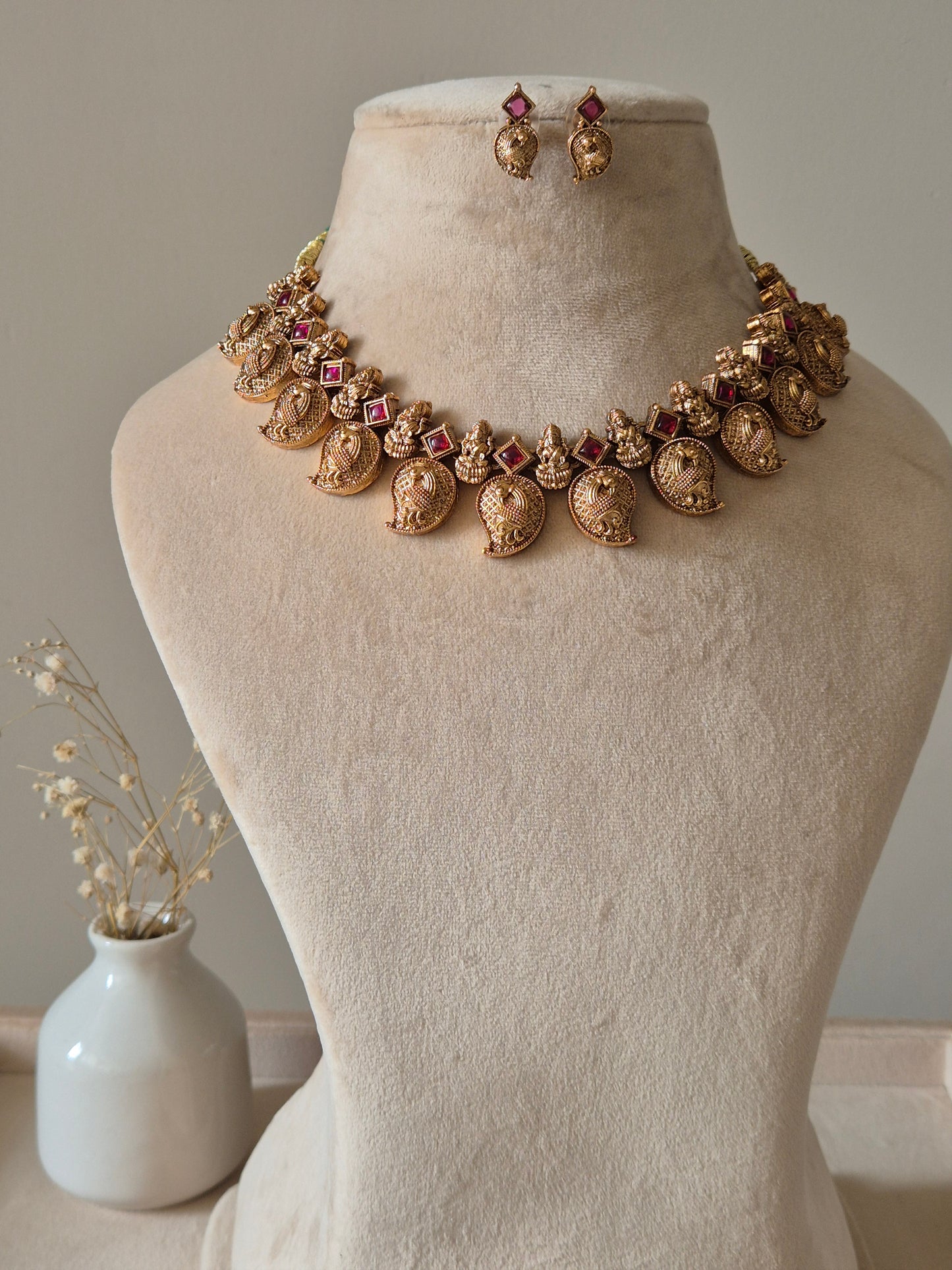 Gold necklace set with matching earrings, Nimai by Naitri, displayed on fabric.