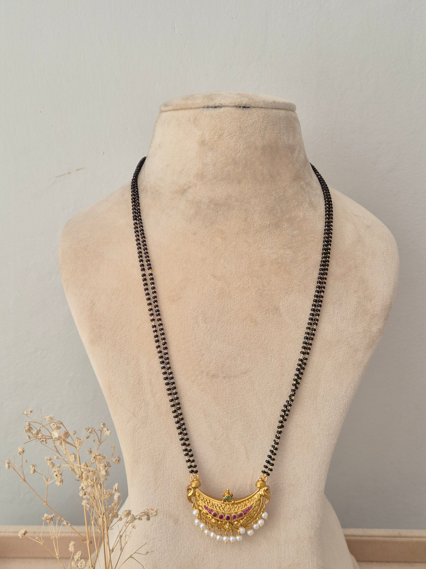 Elegant multi-strand black bead necklace with an artisanal gold crescent motif and dangling pearl accents