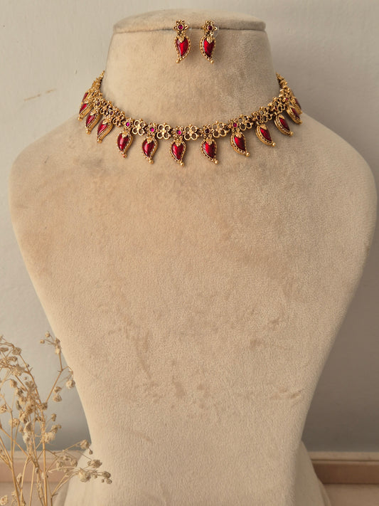 Traditional Indian antique gold choker necklace featuring floral metalwork lined with dangling teardrop-shaped ruby-red stones