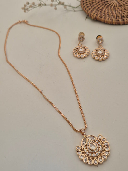 Intricate pendant necklace with a central teardrop stone surrounded by shimmering American Diamonds, paired with matching statement earrings by naitri.in
