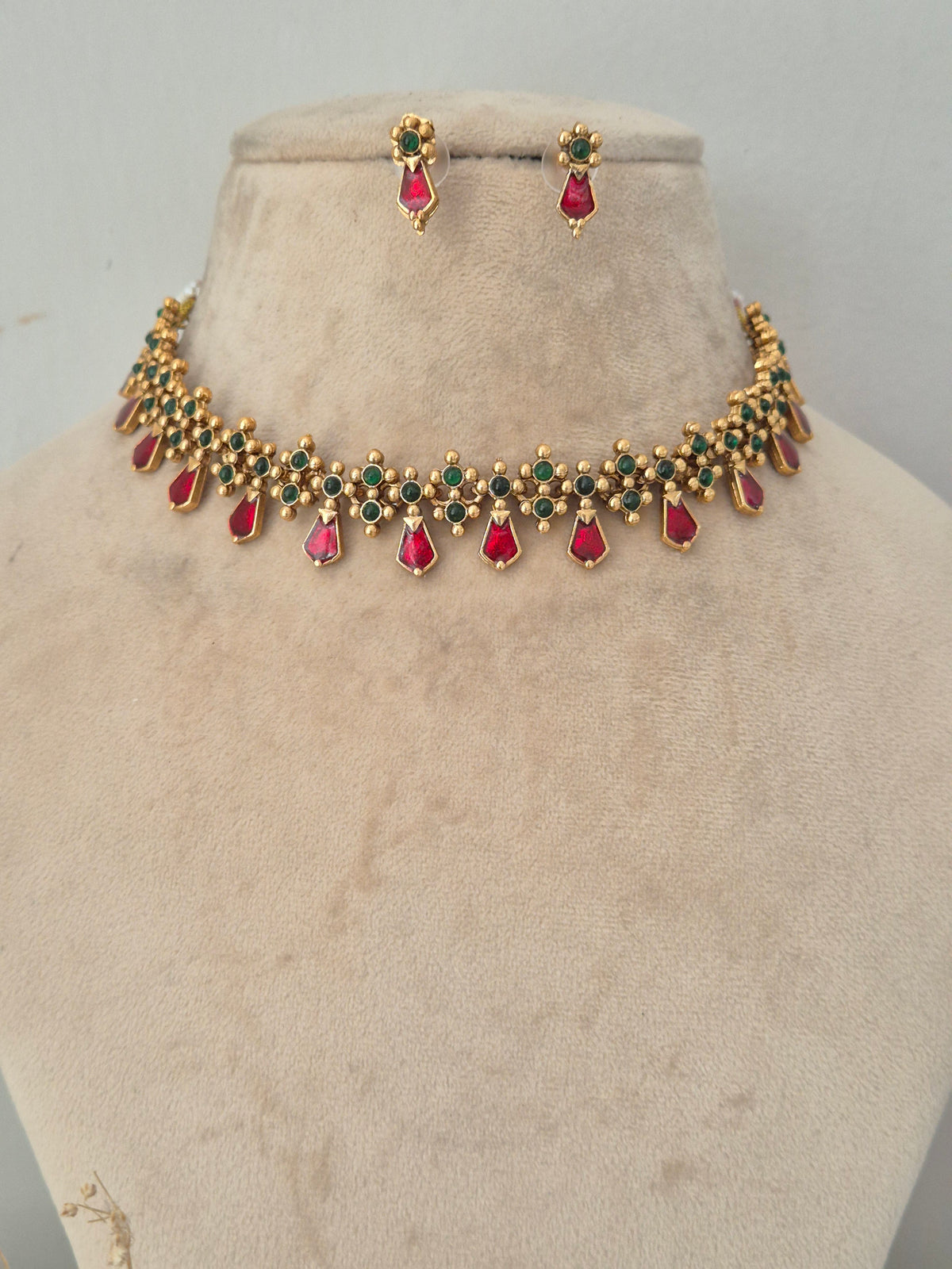 Gold choker necklace and earring set with red and green gemstone accents, Alveera Necklace Set with Red and Green Stones by naitri.in