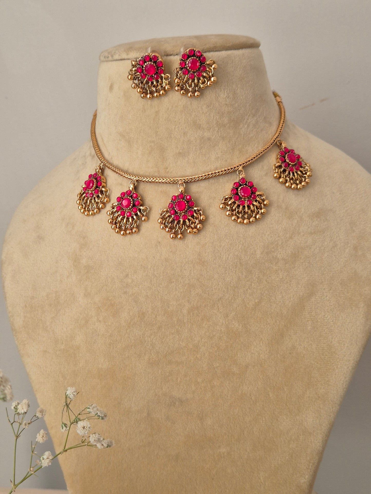 Traditional Indian imitation jewelry set in gold and pink stone, featuring a tiered pendant design on a delicate gold chain by naitri.in