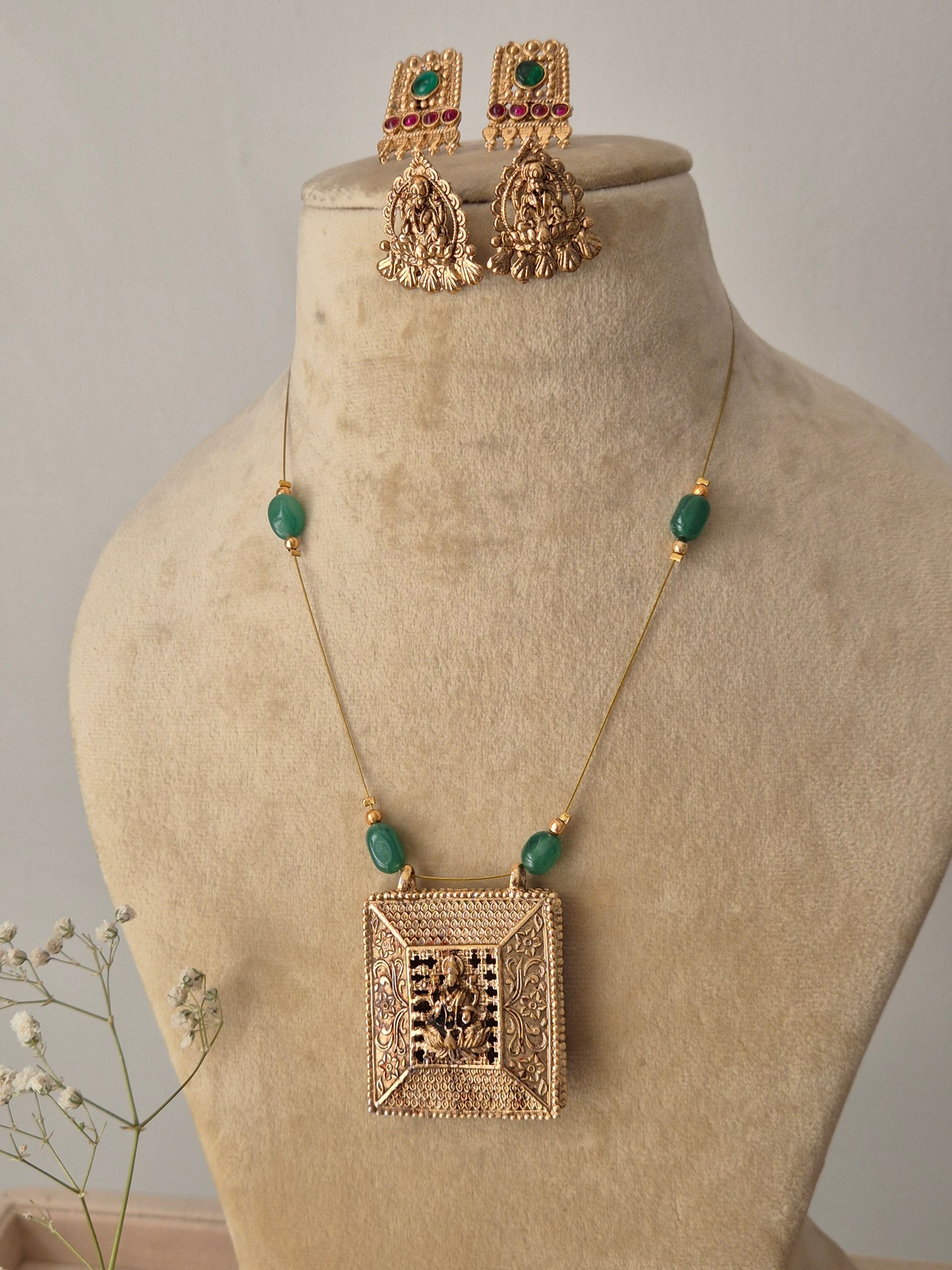 Gold-polished brass necklace set from the Naitri collection, featuring a reversible pendant with intricate metalwork and vibrant stone embellishments on a minimalist chain by naitri.in