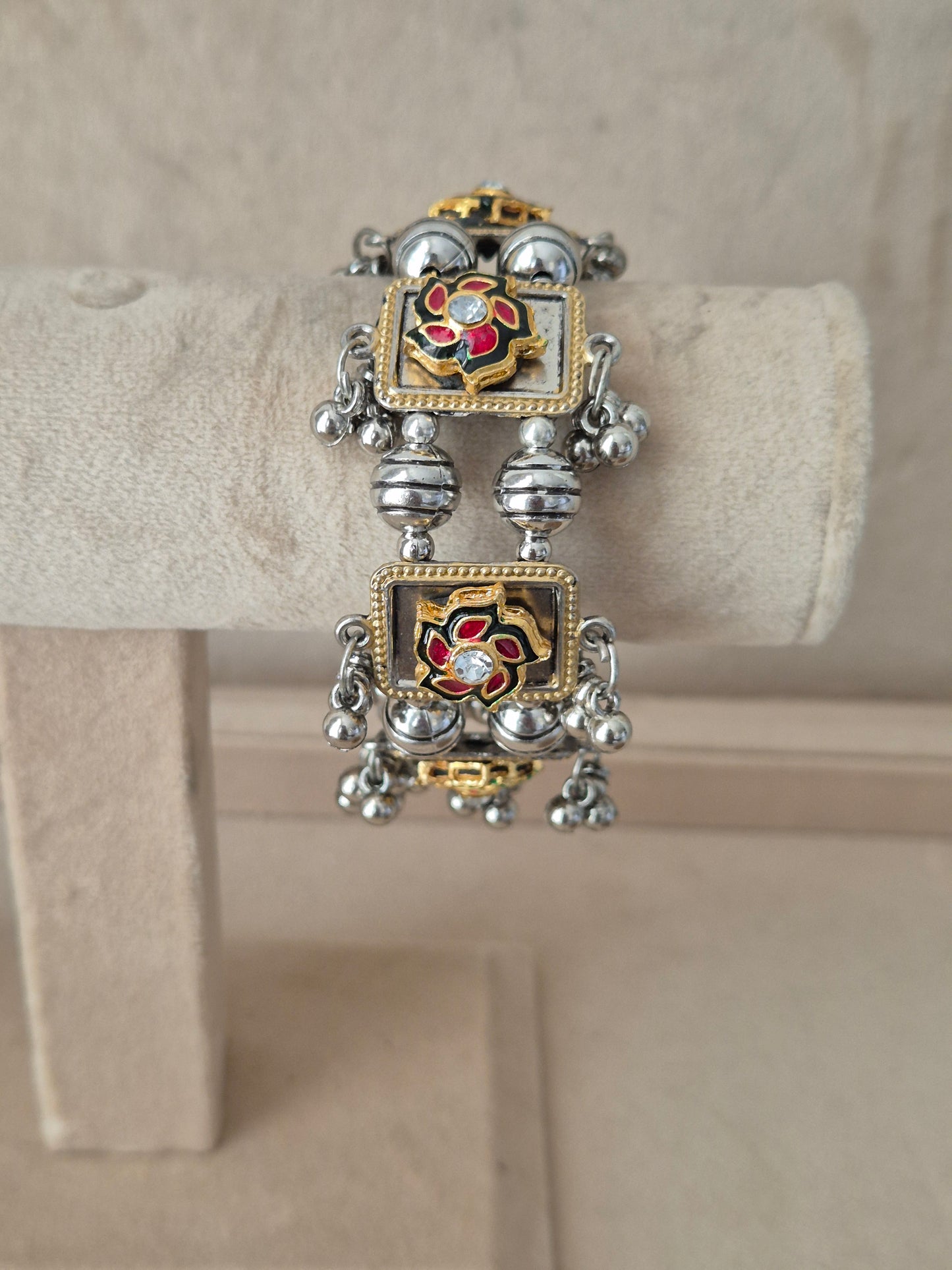 Dual-toned gold and silver Apeksha bangle with floral enamel detailing and hanging ghungroo beads by naitri.in
