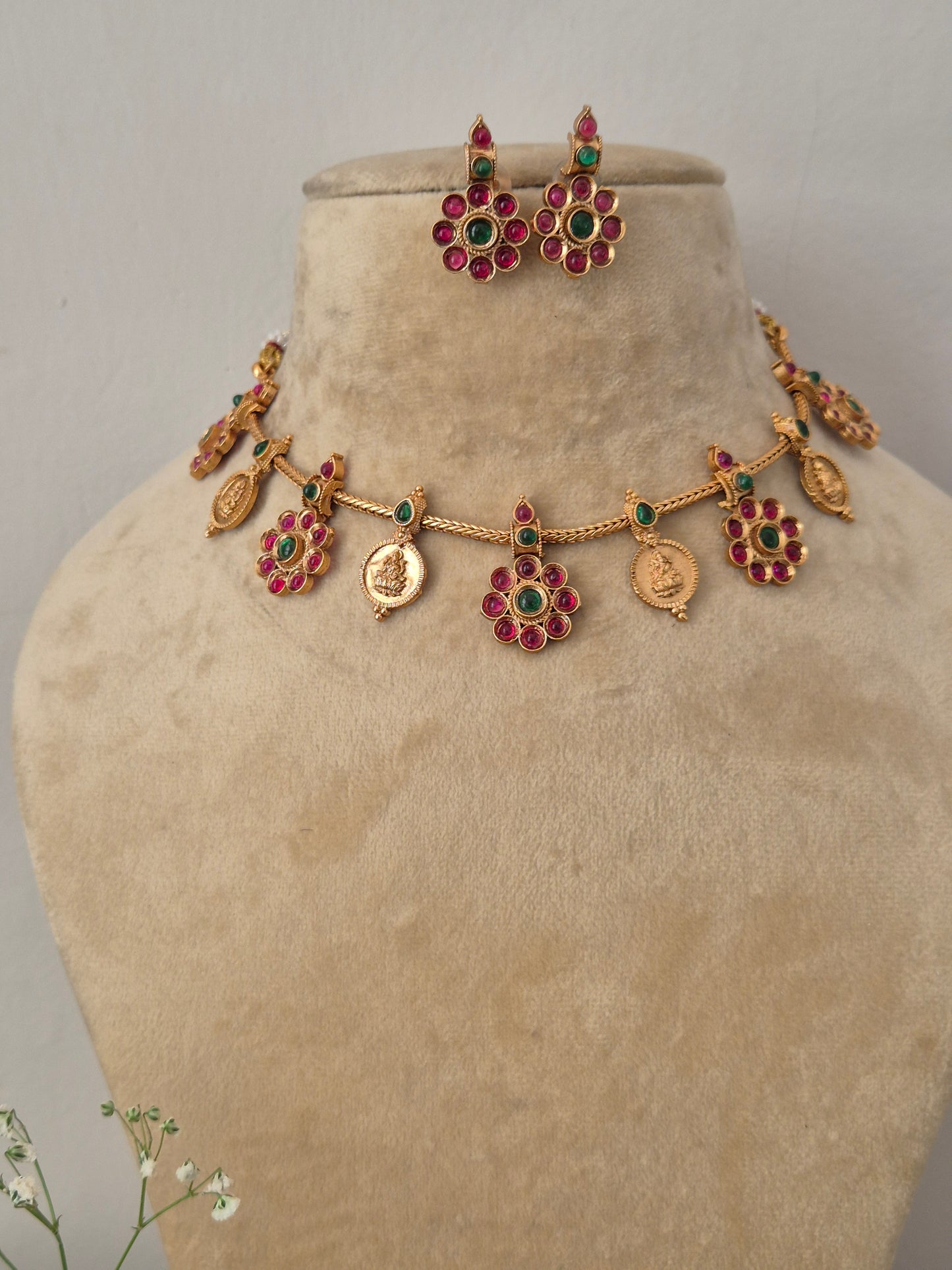 Modern Indian ethnic imitation jewelry set including a textured golden brass alloy choker necklace with vibrant ruby-red and emerald-green stone accents, by naitri.in