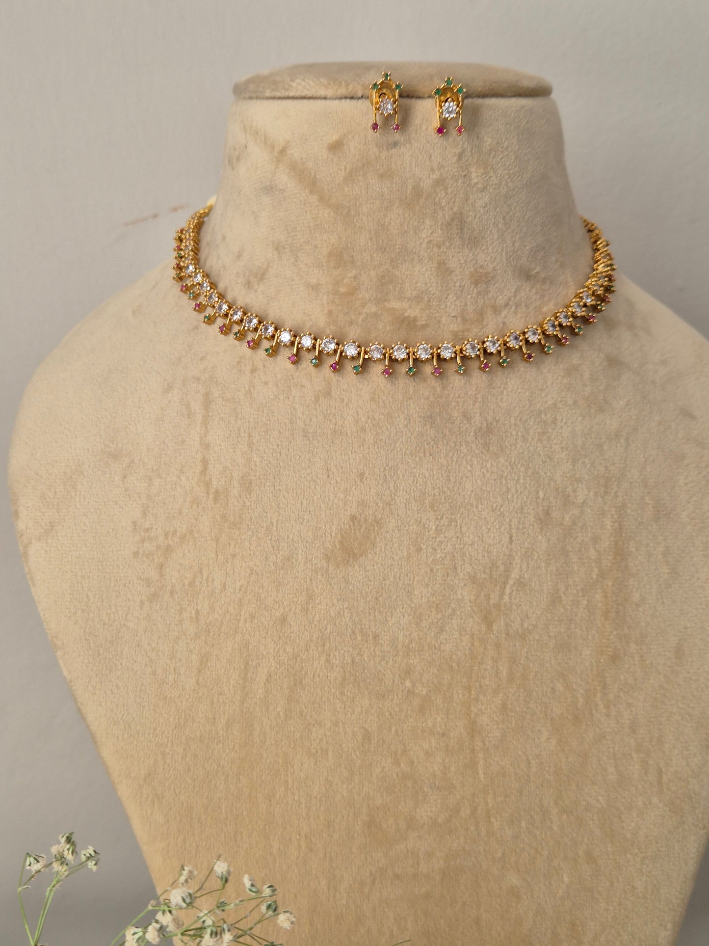 Modern Indian style delicate golden brass alloy American Diamond and ruby-red gemstone choker necklace and earring set from the NAITRI collection by naitri.in