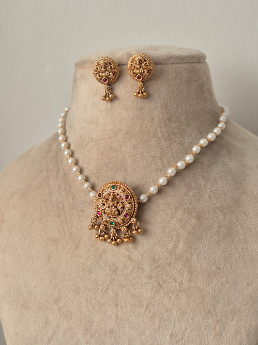 Set of gold jewelry with pearls single chain Antique gold-plated choker necklace featuring a central Goddess Lakshmi motif, hanging golden beads drops by naitri.in