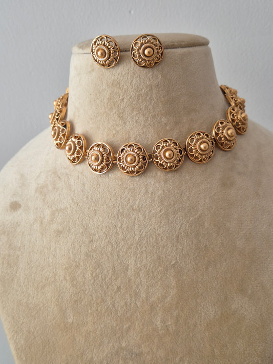 Handcrafted jewelry set in brass alloy with a polished golden finish, featuring traditional textured floral patterns and a contemporary choker design by naitri.in
