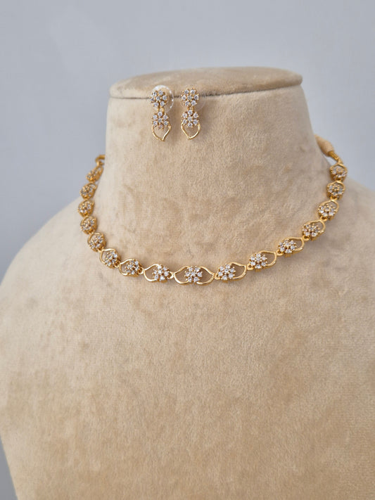 Handcrafted jewelry set in brass alloy with a polished golden finish and clear American Diamond stones in a traditional Indian floral design by naitri.in