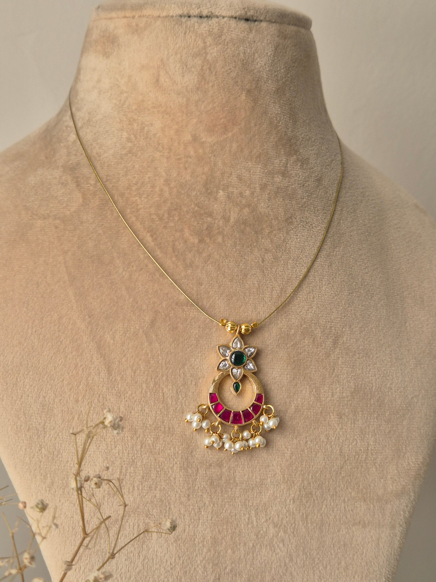 Golden crescent moon pendant necklace with pink and green stonework and small pearl hangings by naitri.in