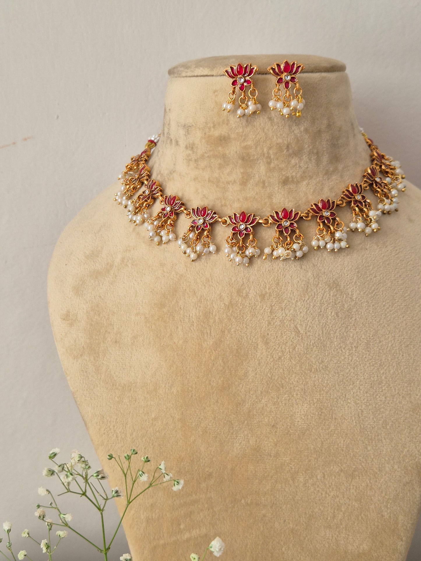 Handcrafted antique gold statement jewelry set showcasing pink stone embellishments and tiny hanging seed pearls, ideal for festive and bridal styling by naitri.in