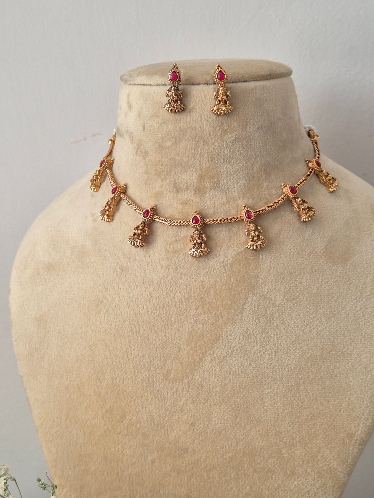 Handcrafted antique gold statement jewelry set showcasing intricate traditional motifs and red gemstone embellishments, ideal for festive styling by naitri.in