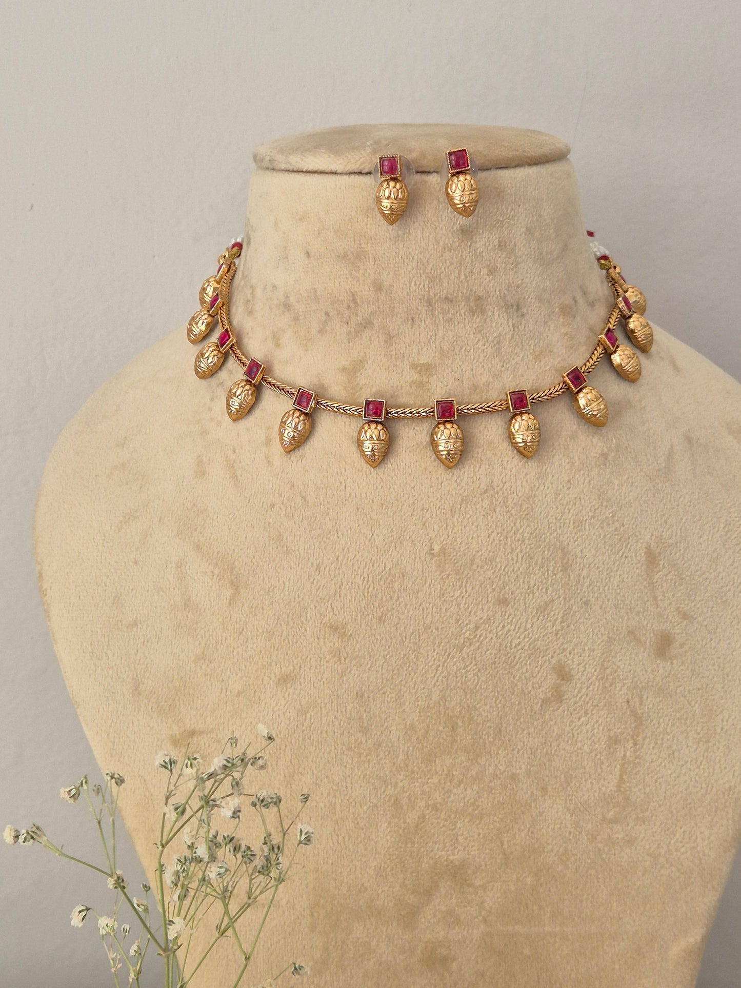 Gold-toned traditional jewelry set with teardrop-shaped gold beads and rectangular red stones, by naitri.in