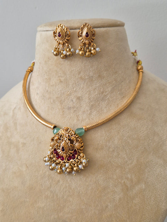 Handcrafted gold-toned necklace featuring an intricate Goddess-inspired pendant, emerald green beads, and matching stone-studded earrings by naitri.in