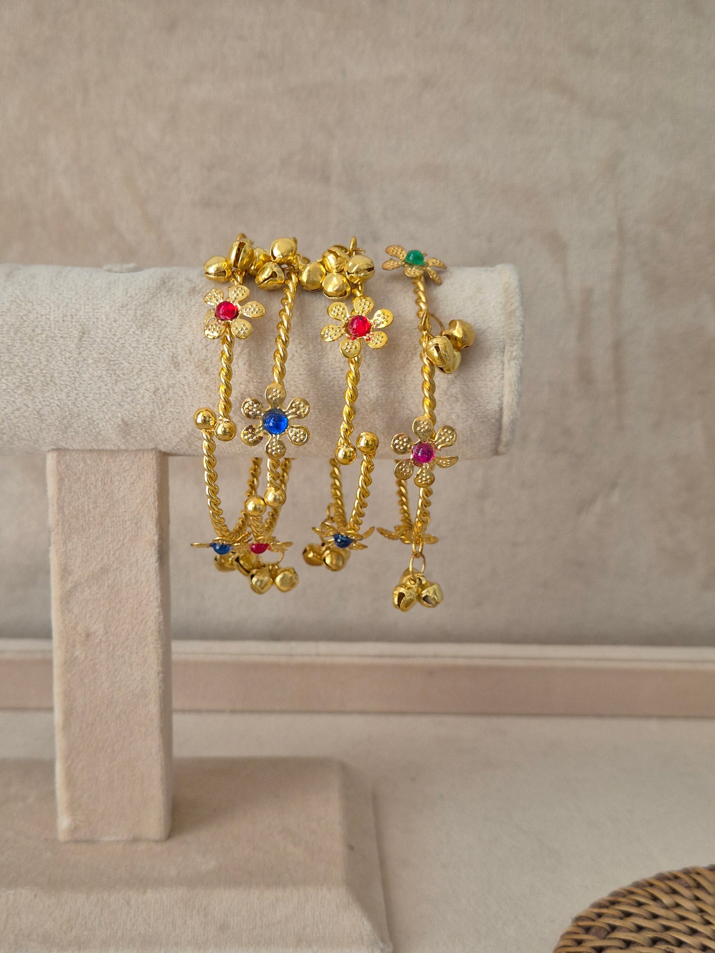 Set of 4 gold Geetanjali bangles with multi-colored floral gemstones and hanging ghungroo chains. Elegant golden ethnic bracelets with traditional festive details and hanging accents by naitri.in