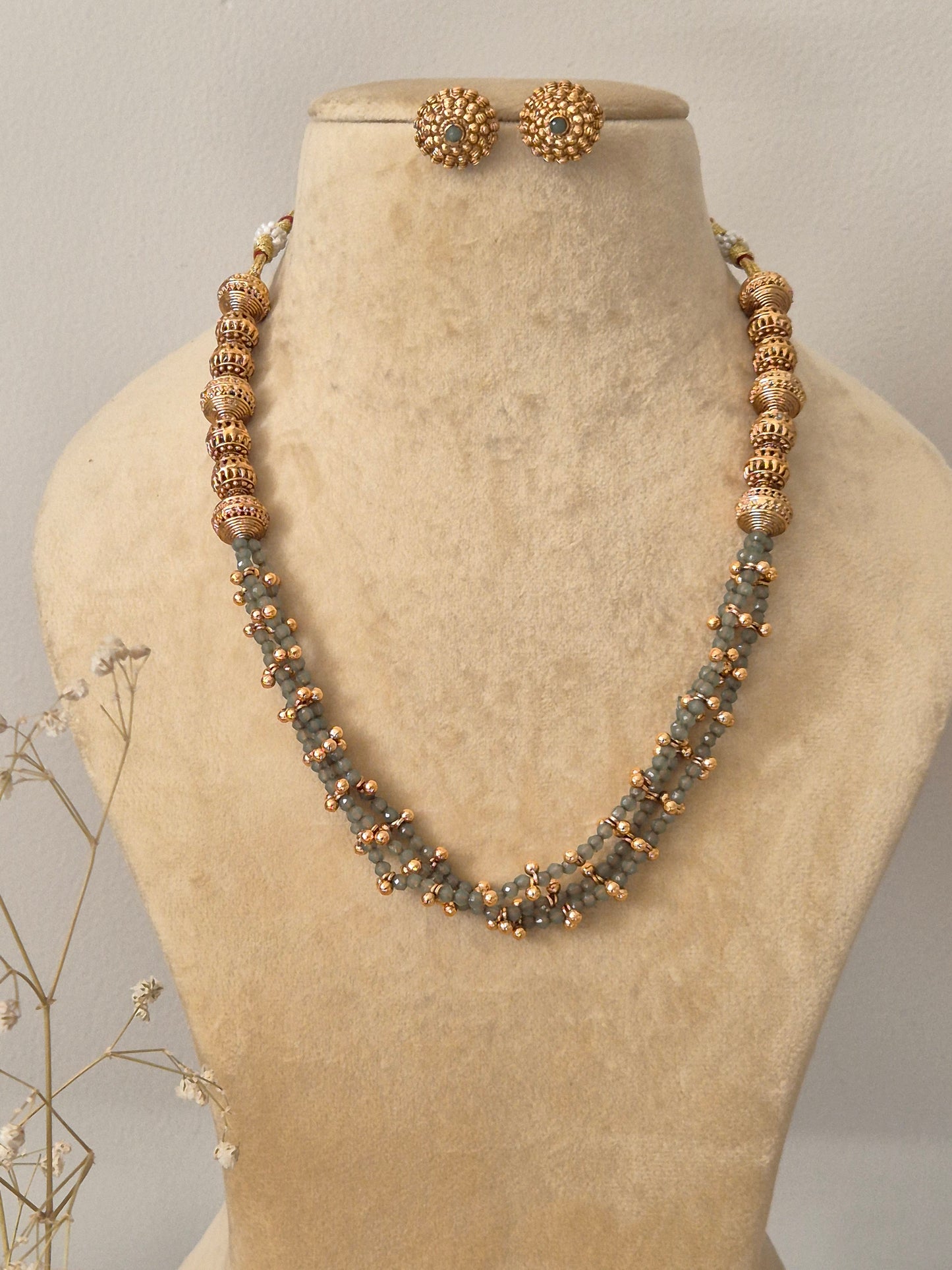 Traditional Gold-Plated Multi-Strand Bead Necklace with Grey Accents and Ethnic Stud Earrings Gold and grey multi-strand beaded necklace with textured gold bead accents and matching stud earrings by naitri.in