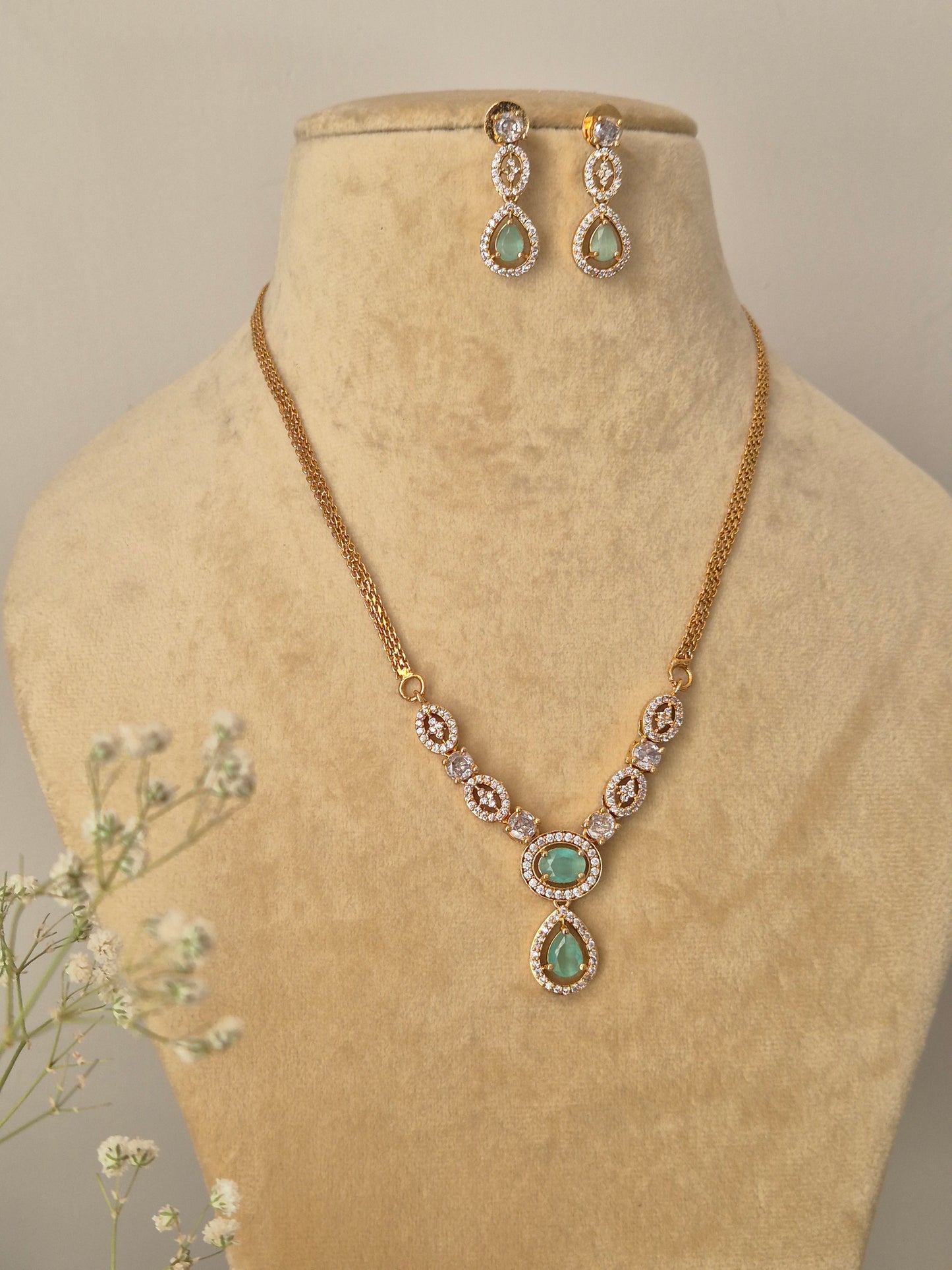 Handcrafted brass alloy necklace set with a polished gold finish and shimmering synthetic green stone embellishments.