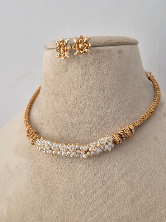 Handcrafted brass alloy ethnic necklace featuring an intricate gold chain design, central pearl cluster detailing, and matching stud earrings by Naitri.in