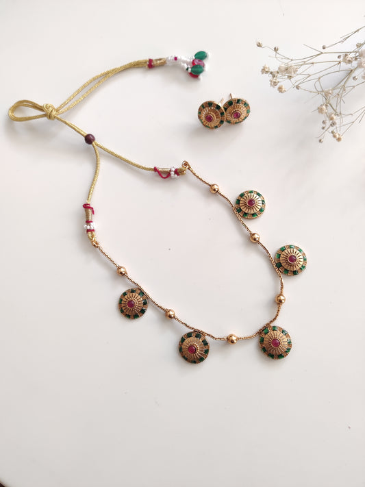 Close-up of ornate temple necklace set showcasing detailed metal craftsmanship with gold and silver tones