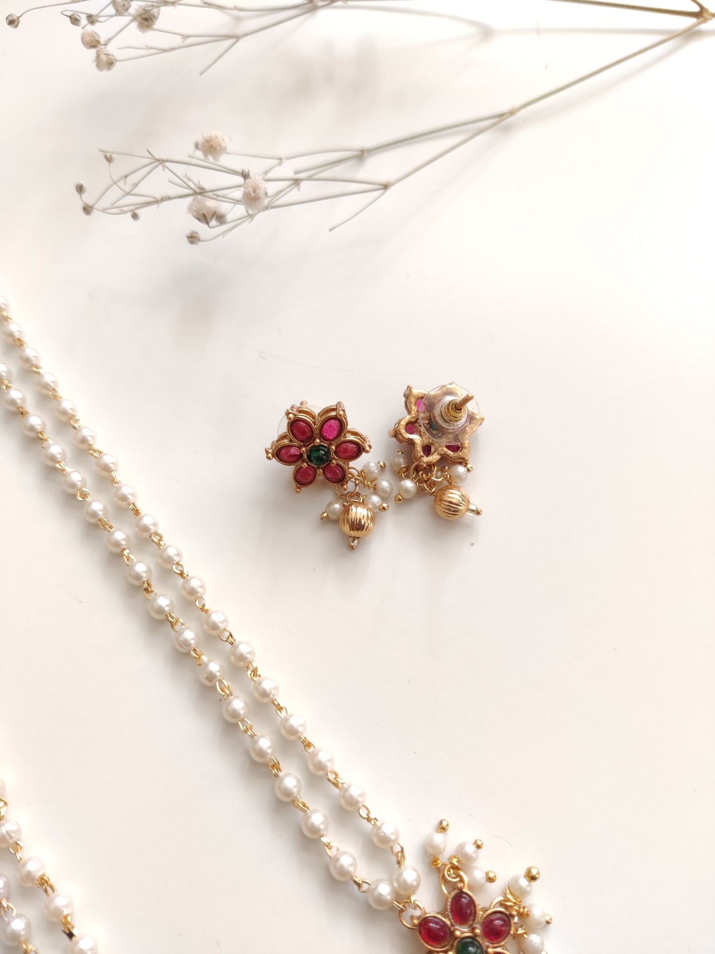Artistic shot of temple necklace set featuring gold, green, and red embellishments and intricate metalwork