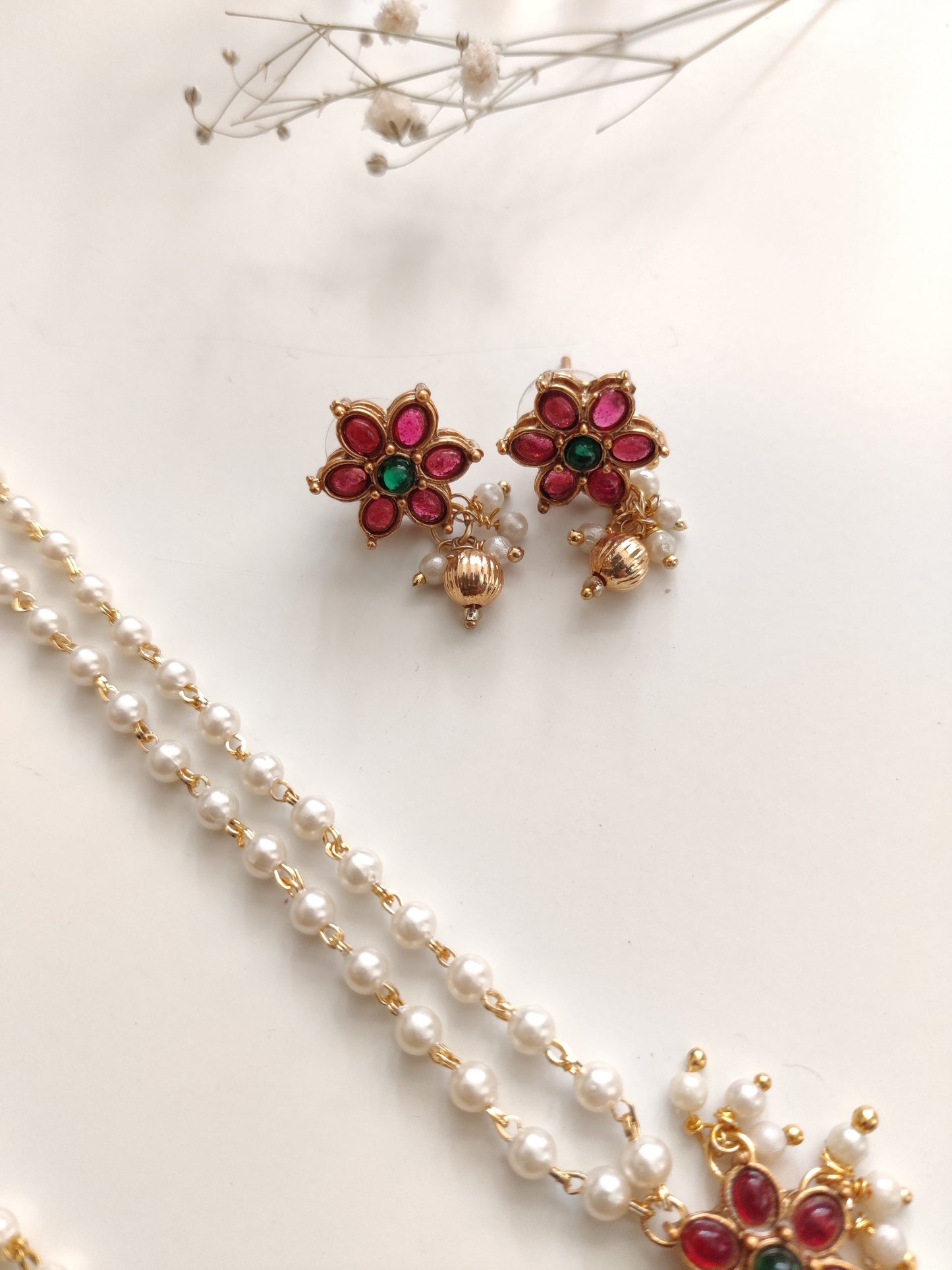 Artistic shot of temple necklace set featuring gold, green, and red embellishments and intricate metalwork
