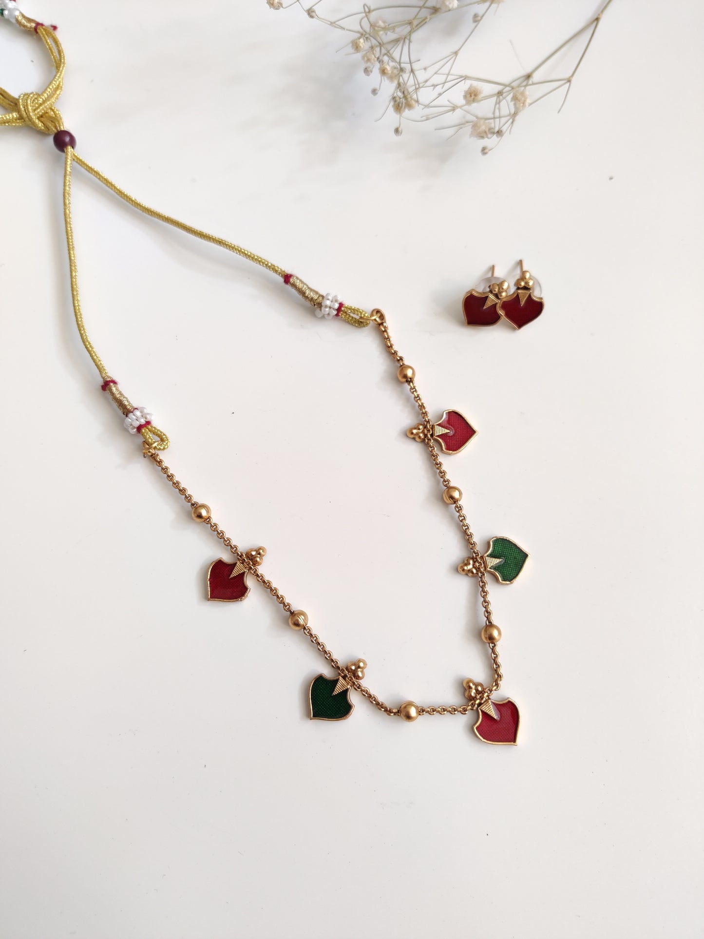 Luxurious temple necklace set with gold, red, and green highlights, draped to display fine artisan work