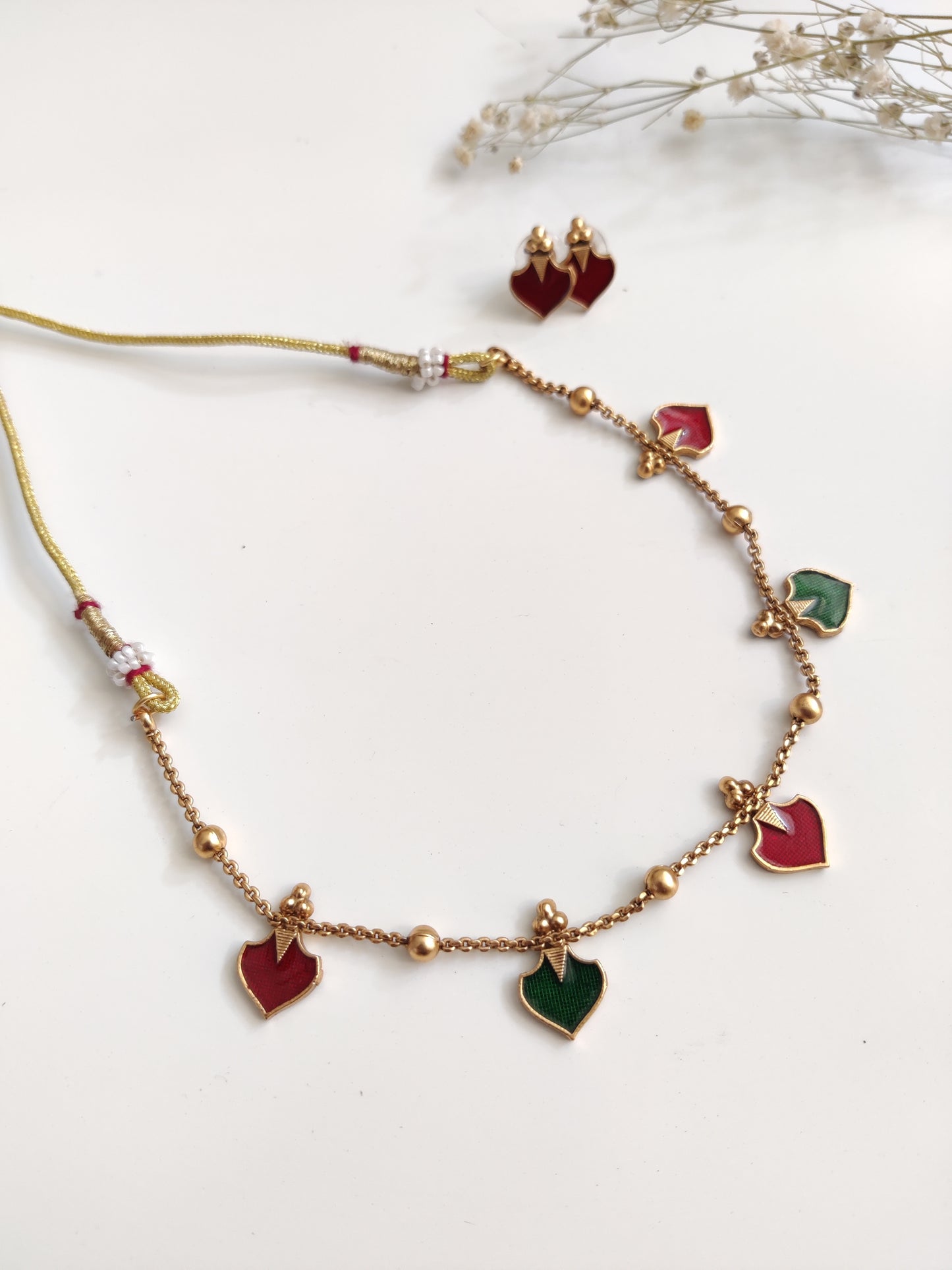 Luxurious temple necklace set with gold, red, and green highlights, draped to display fine artisan work