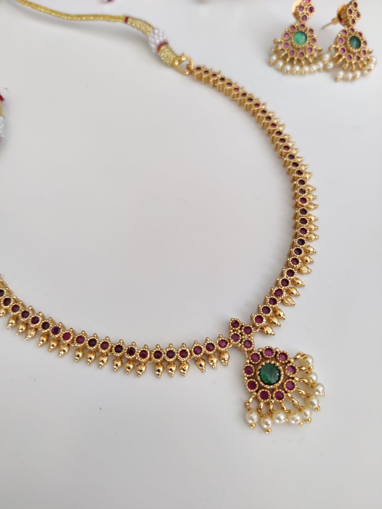 Sophisticated metal alloy necklace set photographed on a plain background to show classic design