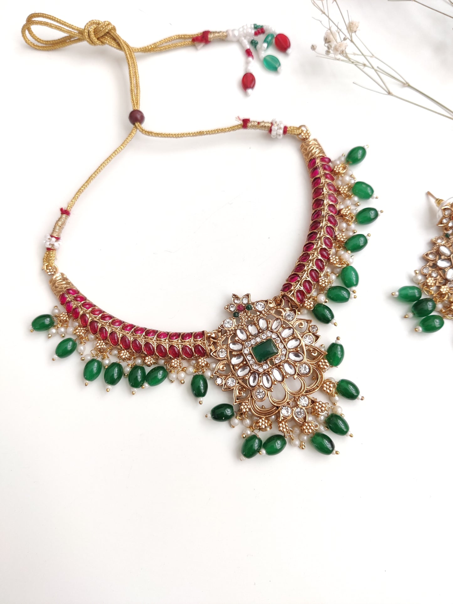 Premium temple necklace set with rich gold, green, and red details photographed on neutral background