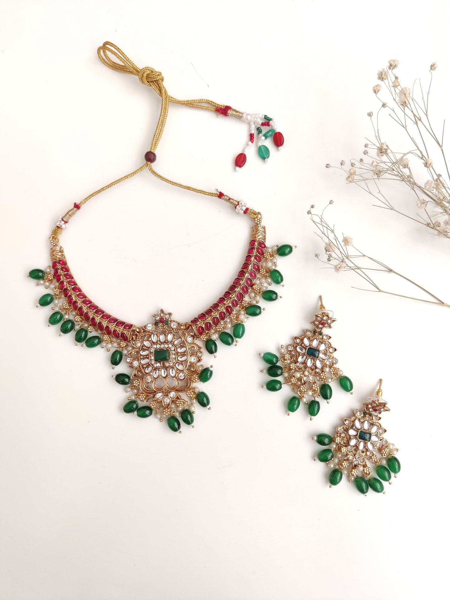 Premium temple necklace set with rich gold, green, and red details photographed on neutral background