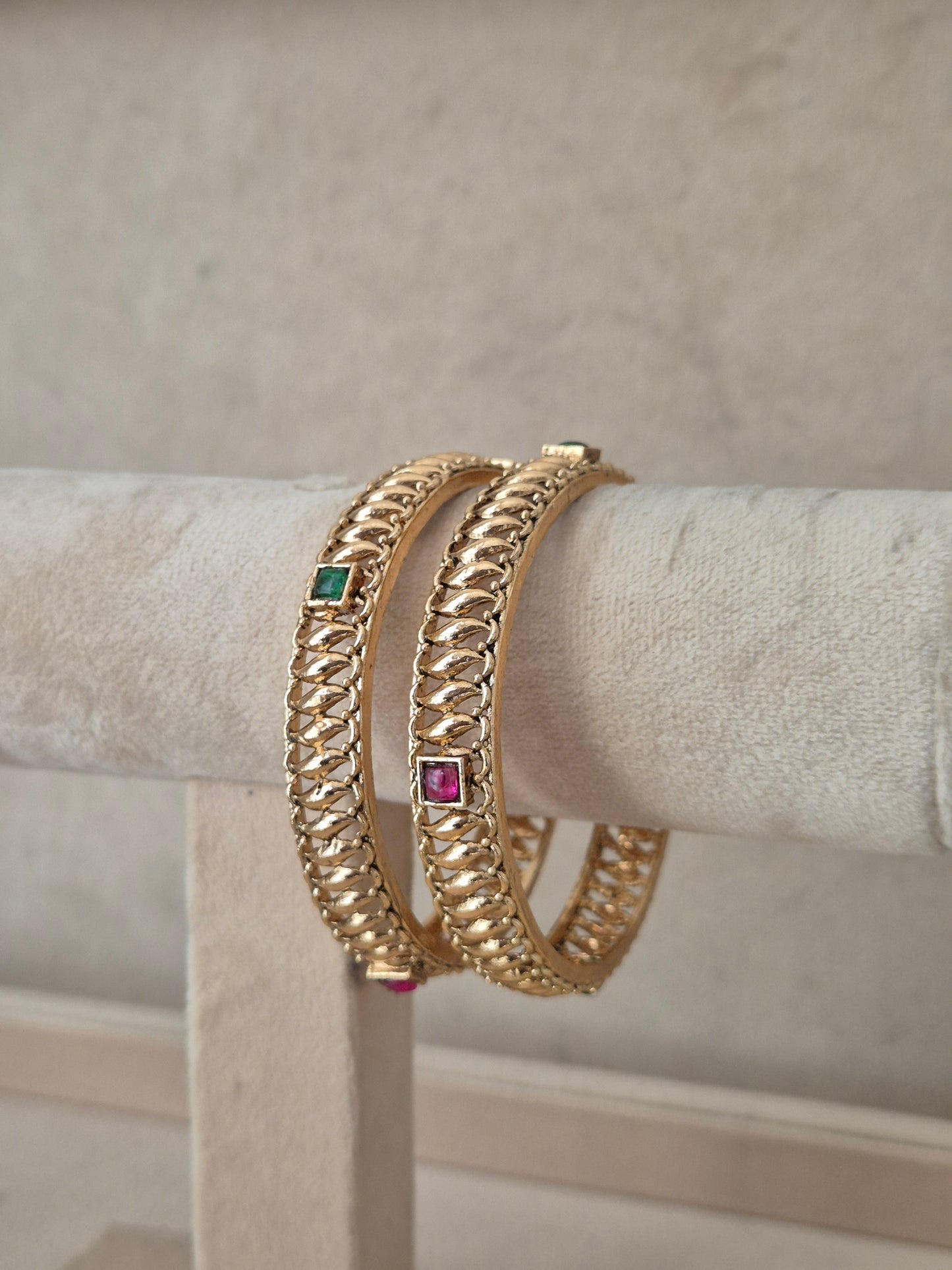 Two gold-plated chain-link bangles with small square green and pink gemstone accents, by naitri.in
