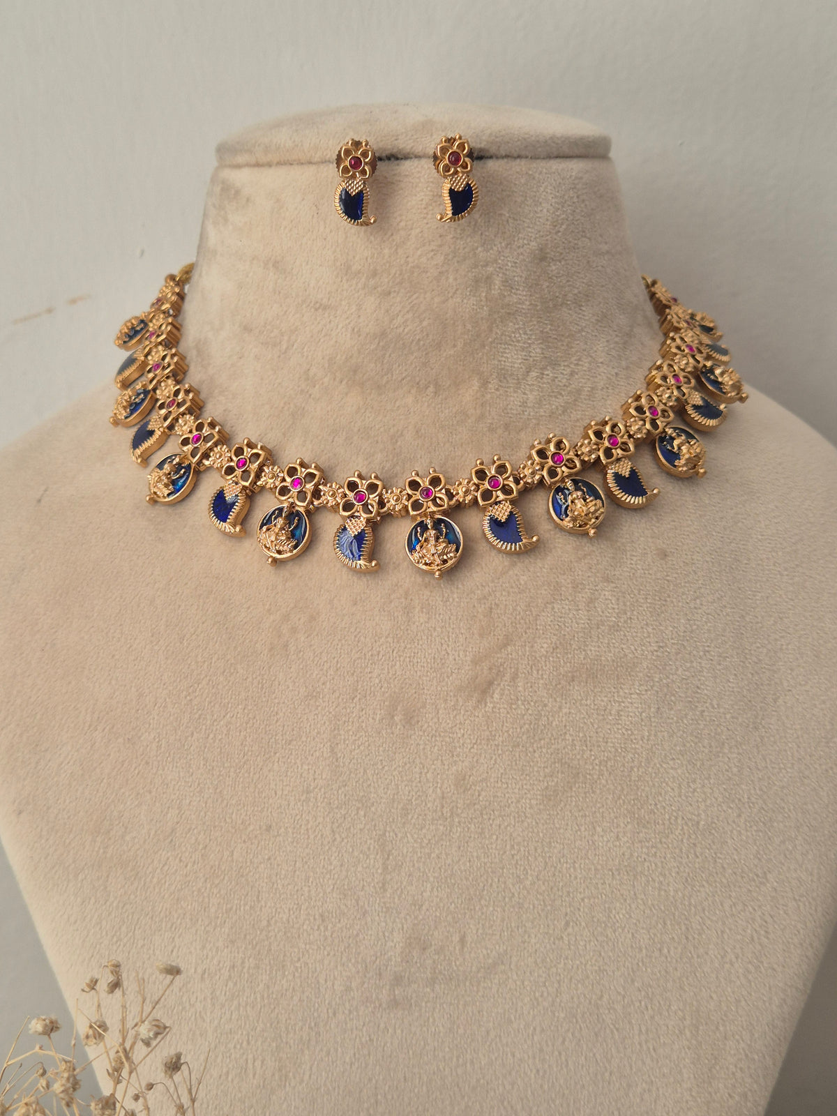Gold-toned jewelry set, featuring a necklace with blue and pink enamel details and matching drop earrings by naitri.in