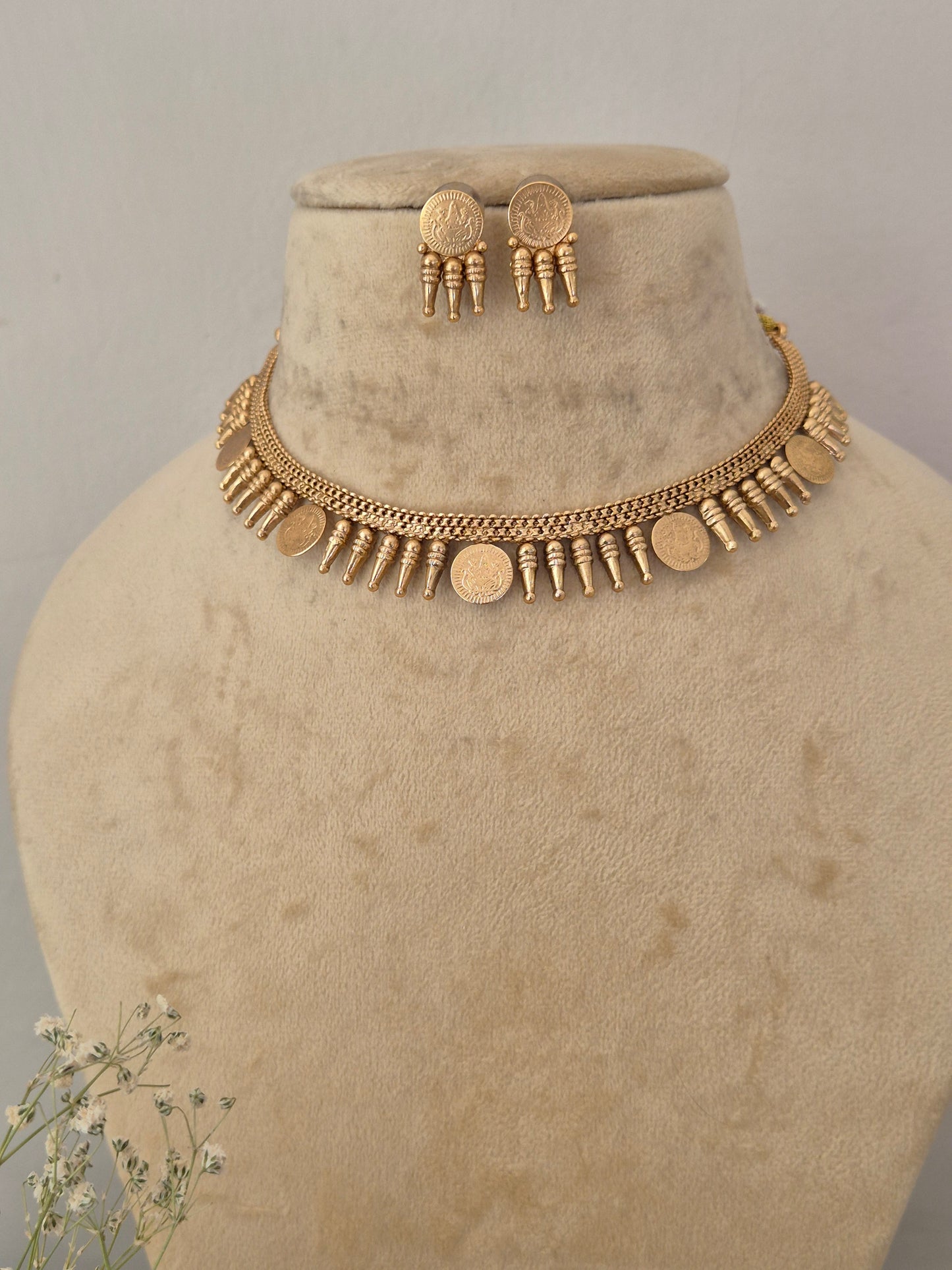 Gold coin-style necklace and matching drop earrings featuring a brass alloy golden ethnic choker and matching textured button earrings for festive wear by naitri.in