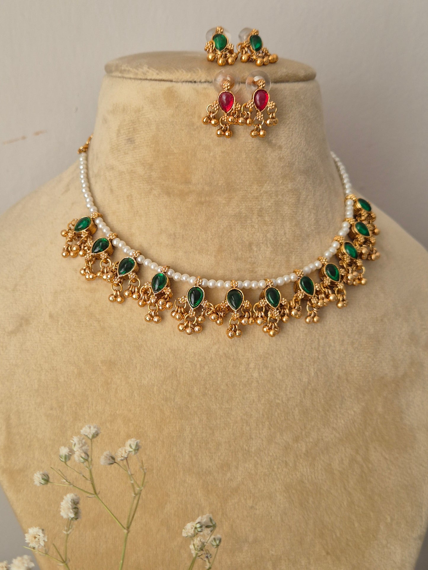 Gold-polished delicate pearl choker with green kemp stone embellishments and matching versatile stud earrings from the Golden Ethnic Jewellery line by naitri.in