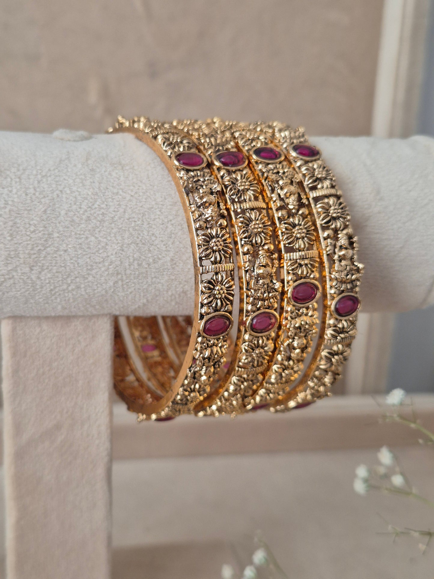 Set of four traditional gold-toned bangles with detailed engraving and red stones by naitri.in