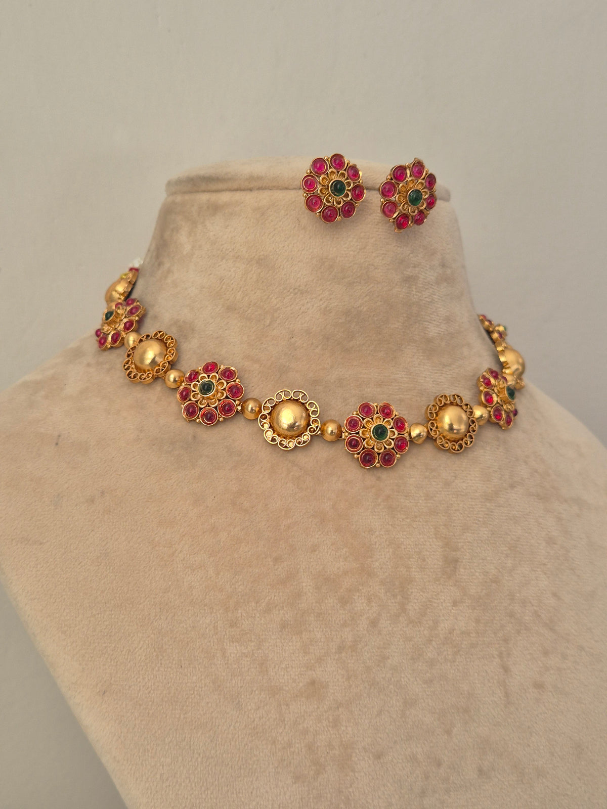 Elegant red gemstone and gold-toned traditional choker jewelry set, Gold-plated choker necklace with red floral gemstones and matching stud earrings by naitri.in