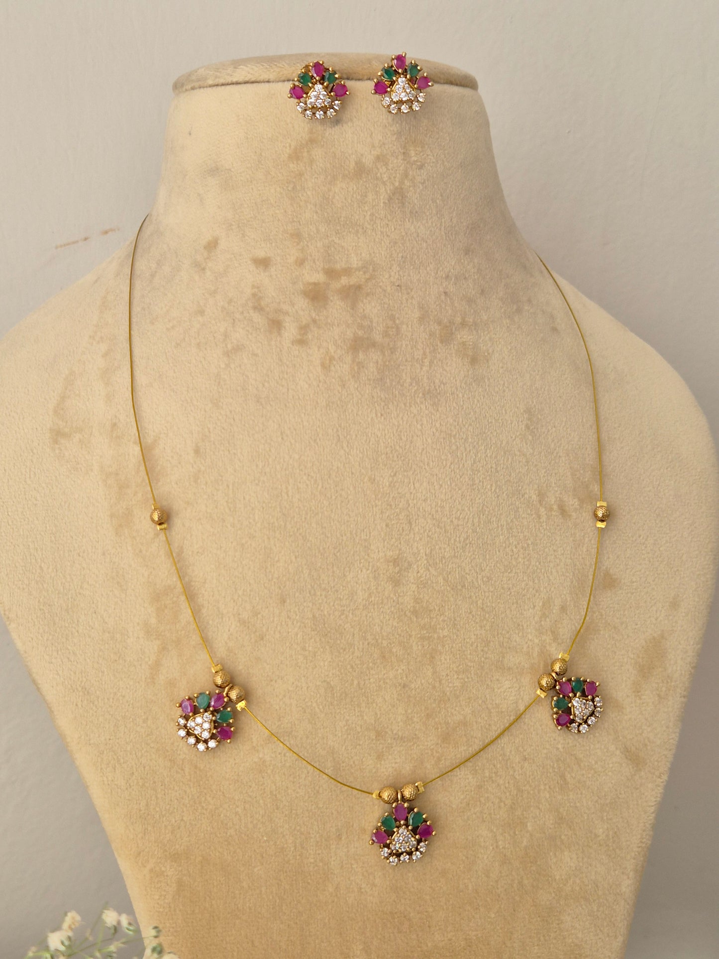 Handcrafted delicate gold chain necklace showcasing small pink and green gemstone floral drops, Modern Indian style delicate golden brass alloy necklace and earring set with floral stone embellishments by naitri.in