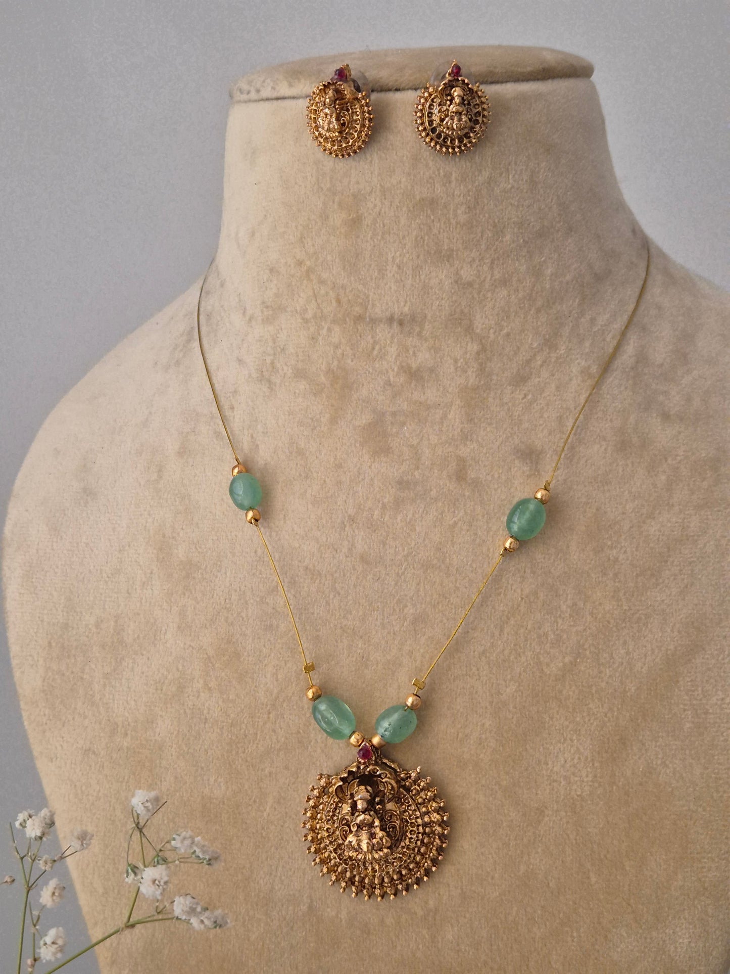 Artisanal gold-finish brass pendant necklace with green stone embellishments and matching studs from the Naitri collection by naitri.in