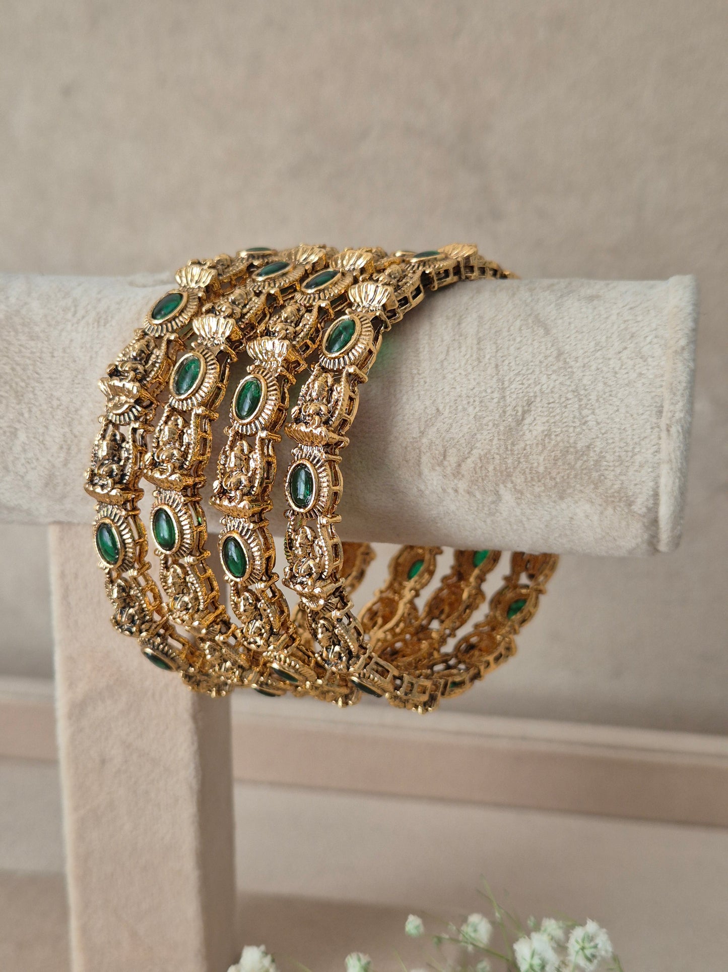 Traditional Indian gold-plated antique bangles adorned with oval green gemstone accents, Antique gold-plated bangle set decorated with green gemstones by naitri.in