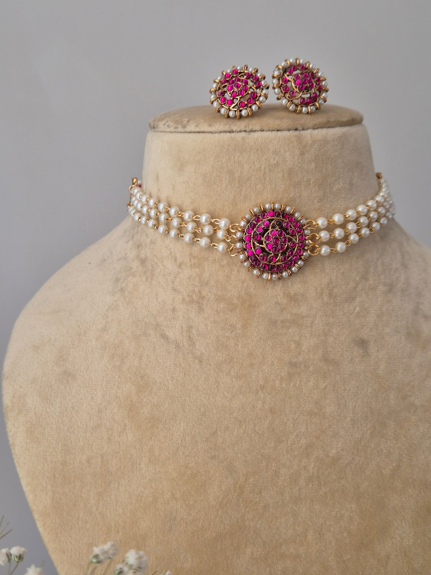White pearl strand necklace with pink stone pendant and matching floral studs and Gold and pearl choker necklace set with pink stone embellishments by naitri.in