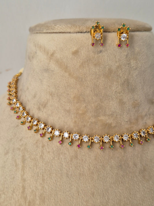 Minimalist gold-toned fine choker necklace adorned with a continuous row of delicate, dangling teardrop motifs in vibrant pinkish-red and sparkling clear crystals, shown with coordinating small drop earrings by naitri.in