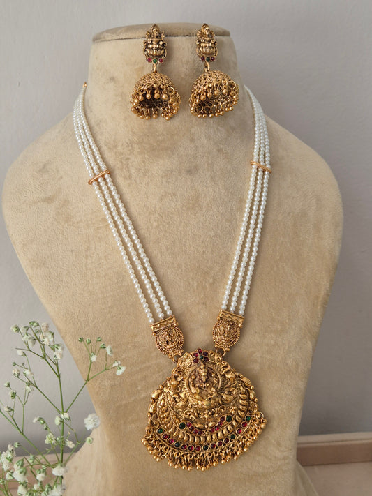 Modern Indian ethnic imitation jewelry set including a multi-layered white pearl strand necklace with a large textured golden temple pendant, by naitri.in