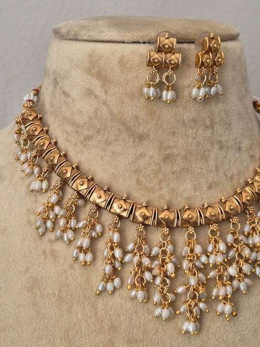 Traditional Indian gold-toned choker necklace set featuring intricate metalwork and cascading white pearl droplets by naitri.in