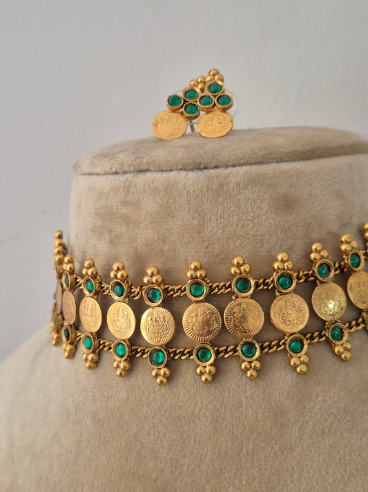 Modern Indian imitation jewelry set featuring an intricate golden brass alloy coin choker necklace with emerald-green gemstone accents, by naitri.in