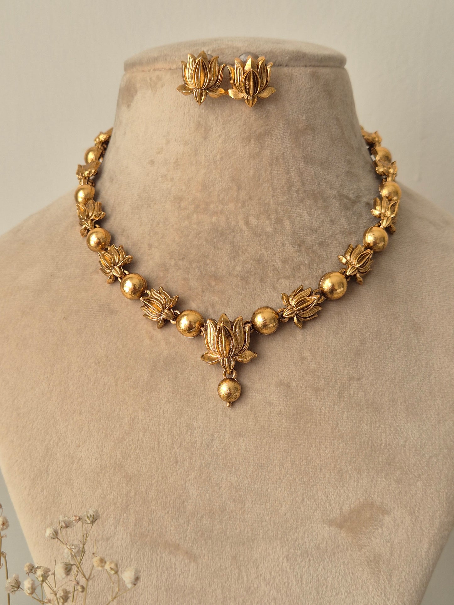 close-up of the Harnoor Necklace Set featuring a golden brass chain with intricate floral and droplet design elements, accompanied by matching floral stud earrings by naitri.in
