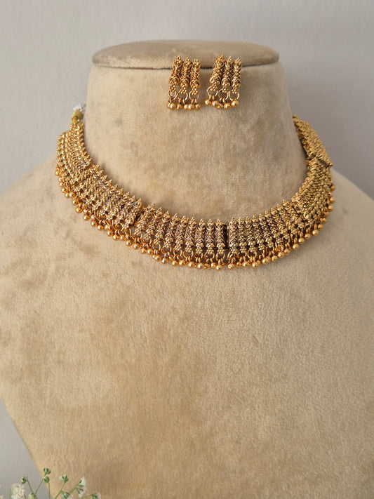 Modern Indian traditional imitation jewelry set including a golden brass alloy collar choker necklace with detailed filigree-style metalwork and delicate hanging beads, by naitri.in