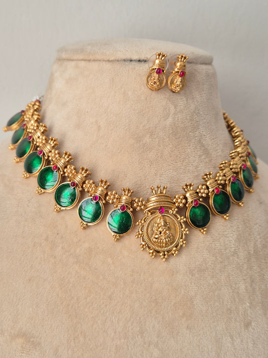 Gold-toned traditional jewelry set featuring a necklace with oval green stones and small red accent stones, plus matching earrings by naitri.in