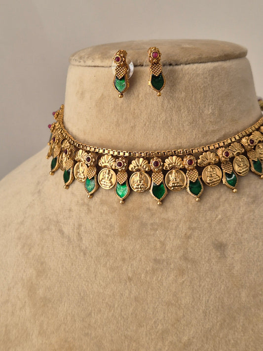 Antique gold-finish choker necklace with intricate metalwork and green teardrop stones, paired with small green stone earrings for a traditional Indian aesthetic by naitri.in